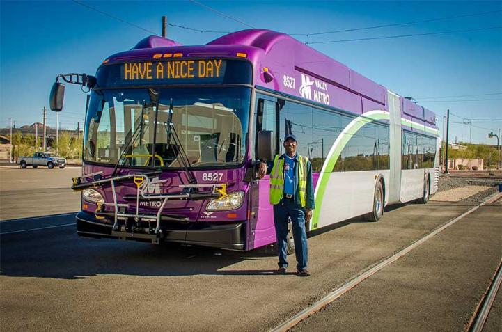 Bus driver stands in front of bus.