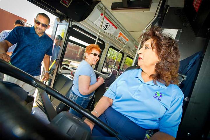 Bus driver welcomes passengers on bus.