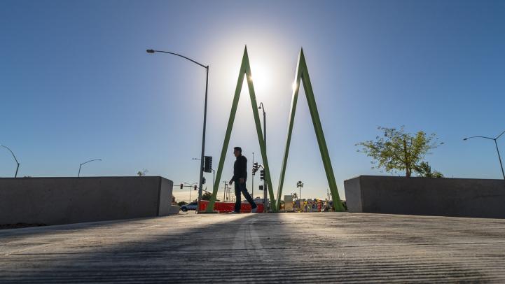 Man walking by light rail station silhouetted by sun