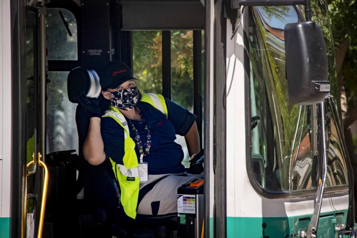 Bus operator wearing mask waves out the window