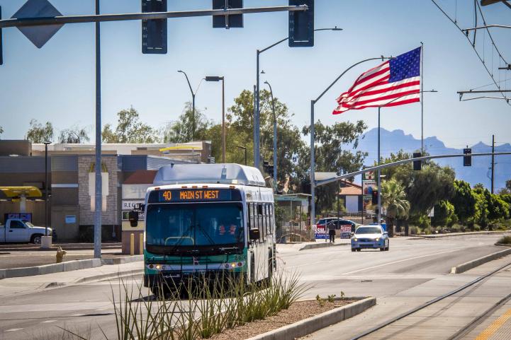 american flag flying over bus driving down street