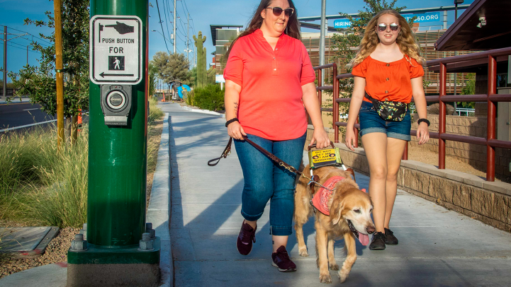 Two women walking with a service dog
