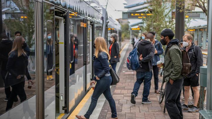 riders wearing face masks enter light rail train