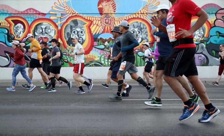 feet of runners in front of colorful mural