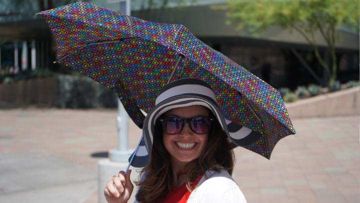 Woman with umbrella, hat, and dazzling smile