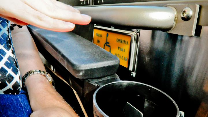 Rider getting ready to push service button aboard bus
