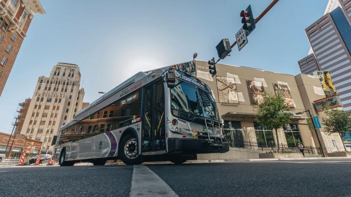 bus turning left in front of buildings and construction cones